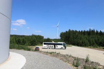 Eingeparkter Bus vor einer Windenergieanlage